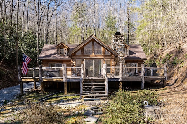 rear view of property featuring log siding, a chimney, stairway, and a deck