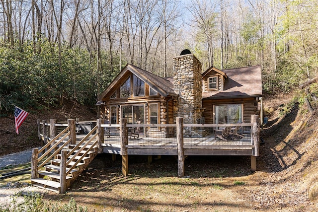 view of front facade featuring a chimney, log exterior, and a deck