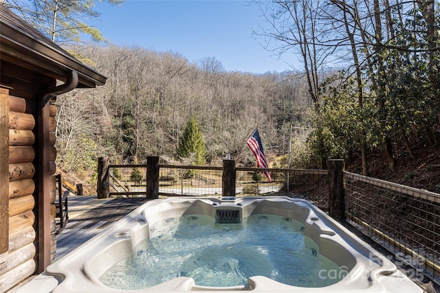 view of pool featuring a forest view and a hot tub