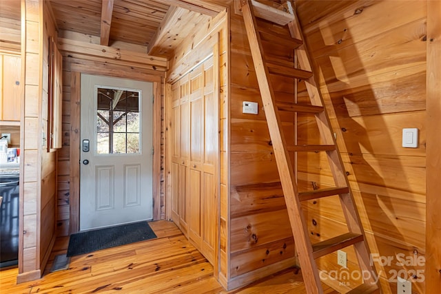 entryway featuring wood ceiling, wood walls, and light wood finished floors