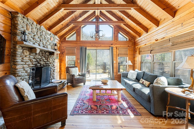 living room with wood ceiling, wood walls, a stone fireplace, wood finished floors, and beamed ceiling