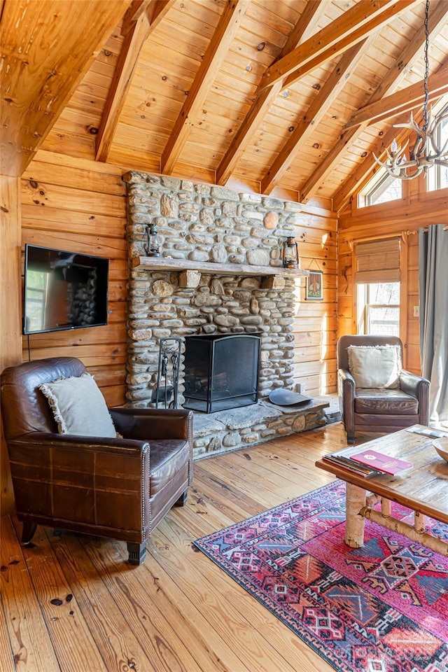 living area with a fireplace, lofted ceiling with beams, wooden walls, wood finished floors, and wooden ceiling