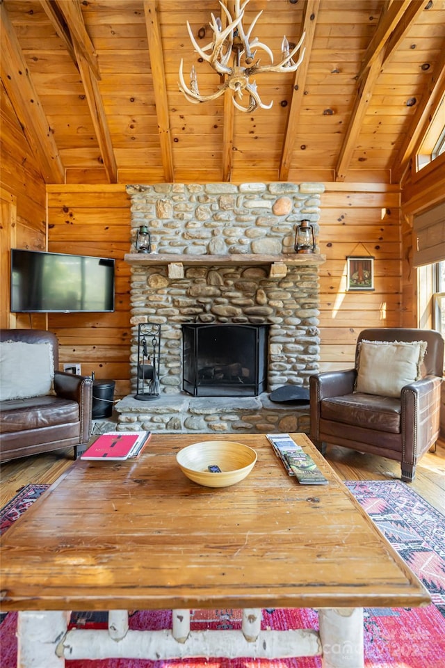 living room featuring lofted ceiling with beams, wood walls, wood ceiling, and a stone fireplace