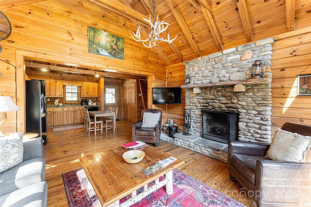 living area with wooden walls, wood ceiling, beamed ceiling, a stone fireplace, and light wood-style floors