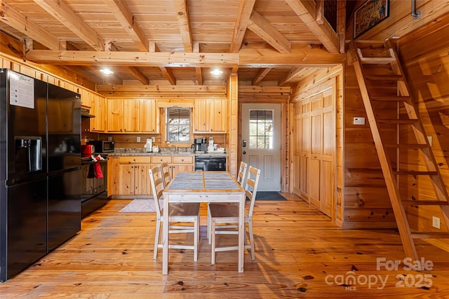 kitchen featuring light countertops, black fridge with ice dispenser, stainless steel microwave, light wood-style floors, and light brown cabinets