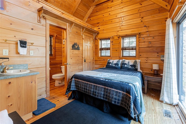 bedroom with wood ceiling, a sink, wooden walls, and lofted ceiling with beams