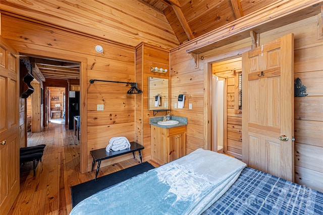 bedroom with lofted ceiling, wood ceiling, a sink, wooden walls, and wood finished floors