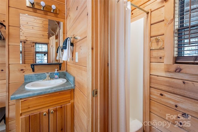 bathroom featuring a shower with curtain, wooden walls, and vanity