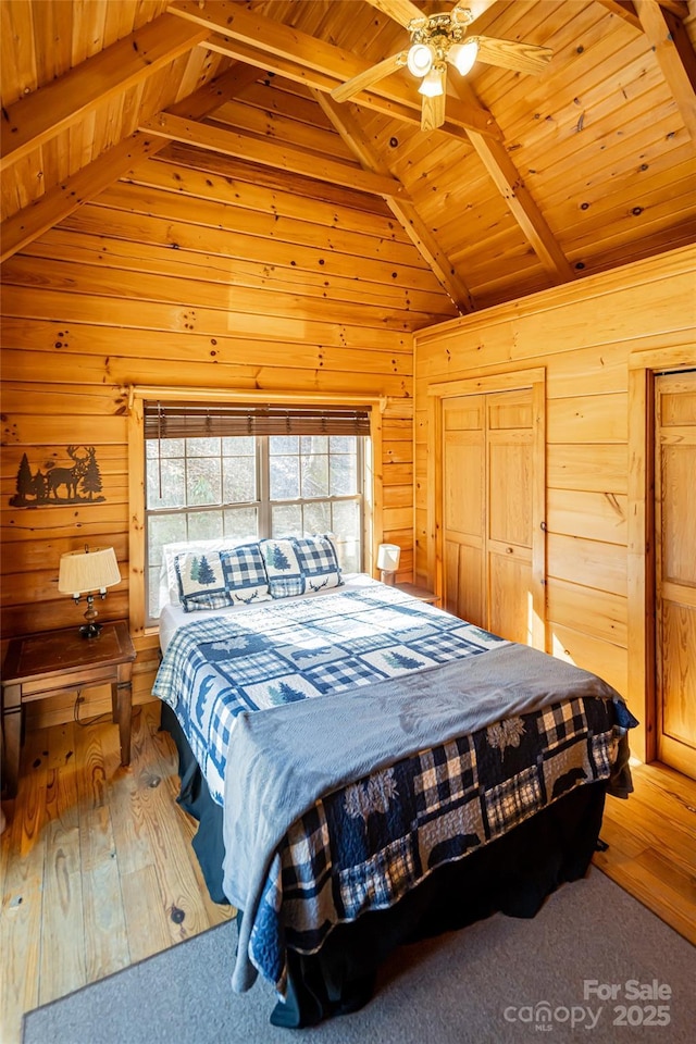 bedroom with wood ceiling, ceiling fan, wood finished floors, vaulted ceiling with beams, and wood walls