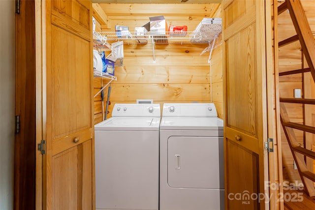 washroom with wood walls, laundry area, and washing machine and clothes dryer