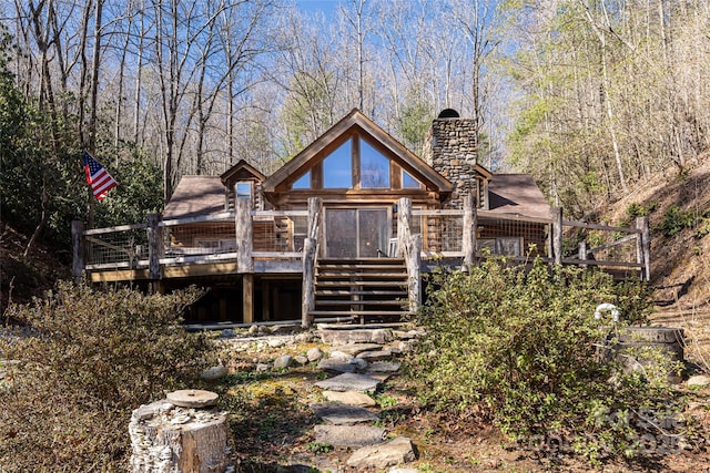 back of house with a chimney and a wooden deck