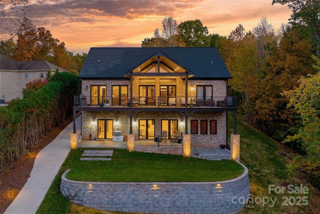 back house at dusk featuring a yard, a patio area, and french doors