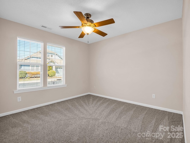 carpeted spare room featuring a ceiling fan, visible vents, and baseboards