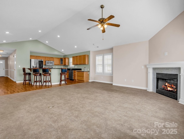 carpeted living room with recessed lighting, baseboards, a warm lit fireplace, and ceiling fan