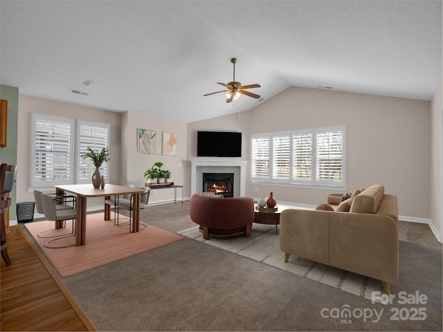 living room with a wealth of natural light, visible vents, a ceiling fan, and vaulted ceiling