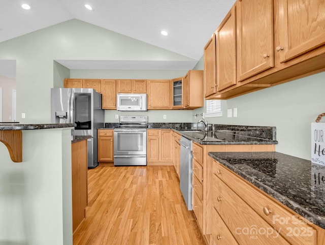 kitchen with dark stone counters, light wood-style flooring, glass insert cabinets, and appliances with stainless steel finishes