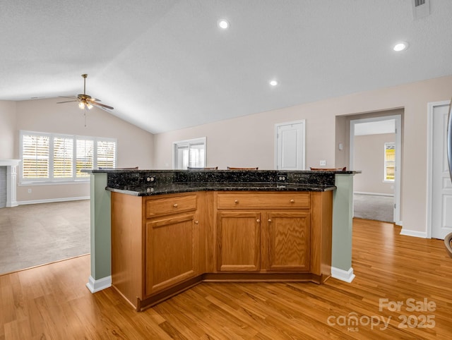 kitchen featuring visible vents, light wood finished floors, ceiling fan, and vaulted ceiling