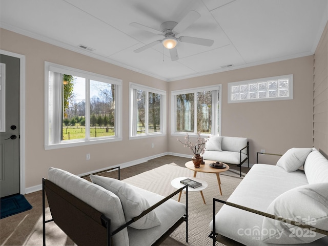 living room with visible vents, baseboards, crown molding, and a ceiling fan