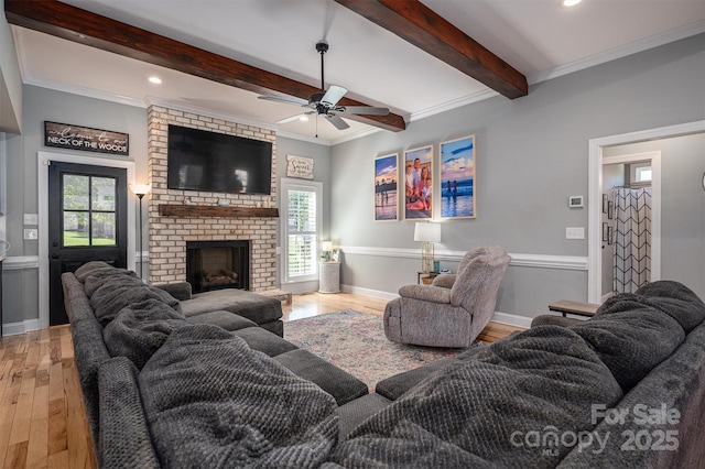 living room featuring light wood-type flooring, ornamental molding, and beam ceiling