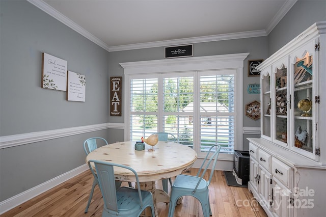 dining room with crown molding, baseboards, and light wood-type flooring