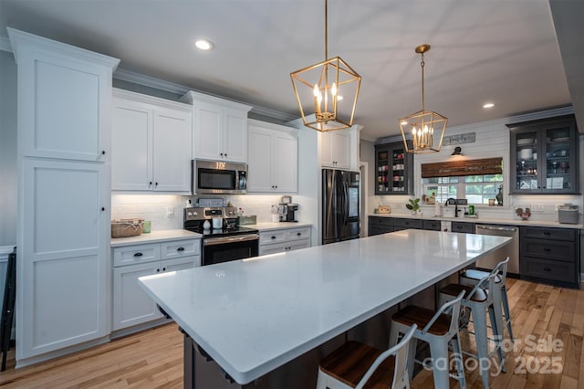 kitchen featuring glass insert cabinets, stainless steel appliances, a kitchen bar, and ornamental molding