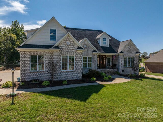 view of front of property featuring brick siding, a front yard, and a shingled roof