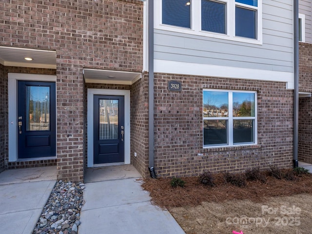 view of exterior entry featuring brick siding