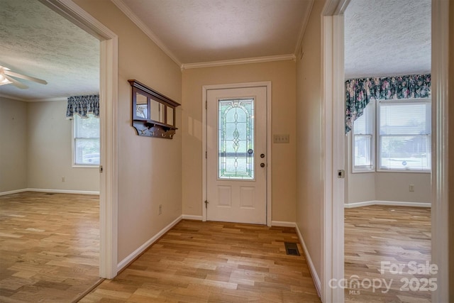 entryway with a ceiling fan, a textured ceiling, visible vents, baseboards, and light wood finished floors