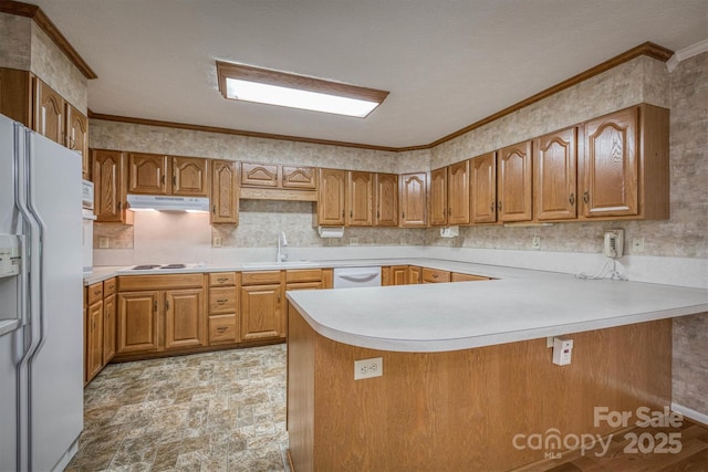 kitchen featuring brown cabinetry, crown molding, a peninsula, white appliances, and light countertops