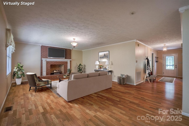 living area with visible vents, ornamental molding, and wood finished floors