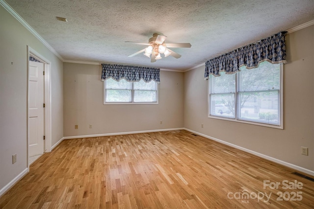spare room with crown molding, a ceiling fan, visible vents, and light wood-style floors
