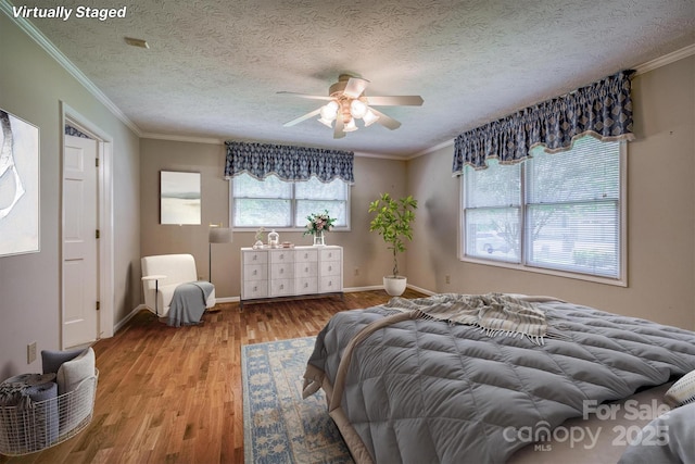 bedroom with a ceiling fan, a textured ceiling, wood finished floors, baseboards, and ornamental molding