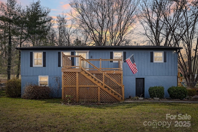 back house at dusk with a yard and a deck