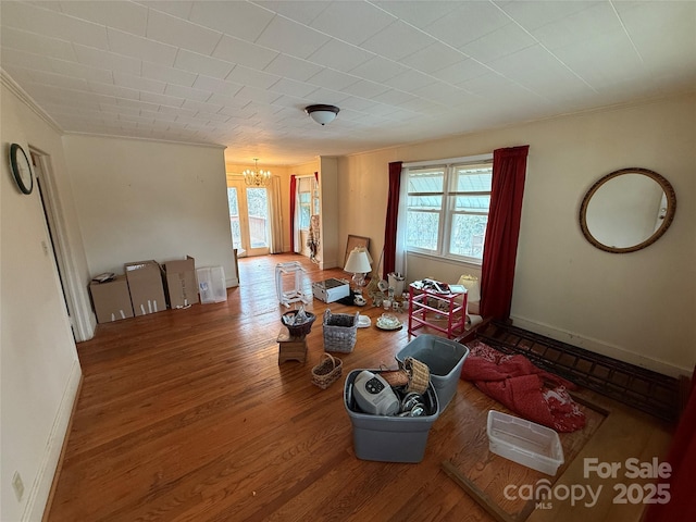 living room with hardwood / wood-style flooring, ornamental molding, and an inviting chandelier