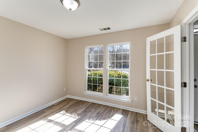 spare room featuring baseboards, visible vents, and light wood-style floors