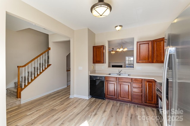 kitchen featuring light wood-style flooring, stainless steel appliances, a sink, baseboards, and light countertops