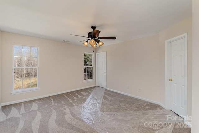 spare room with light carpet, ceiling fan, visible vents, and baseboards