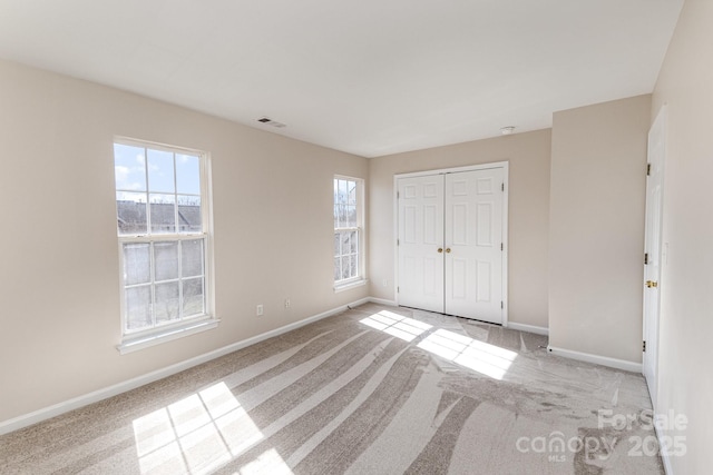 unfurnished bedroom with baseboards, visible vents, and light colored carpet