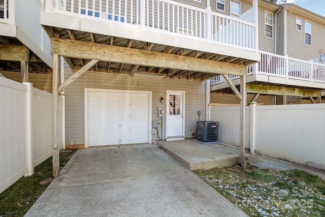 garage with concrete driveway, cooling unit, and fence