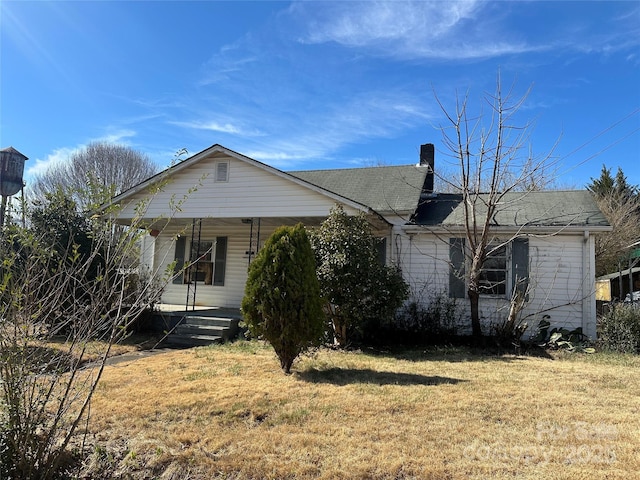 rear view of property with covered porch and a lawn