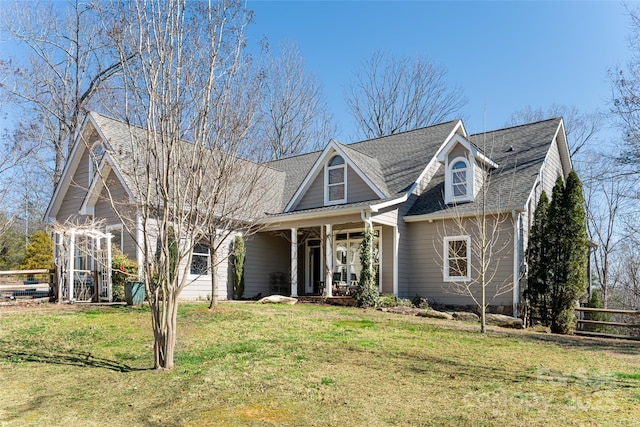 view of front facade featuring a porch, a front yard, roof with shingles, and fence