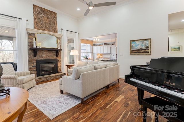 living area featuring ceiling fan, dark wood-type flooring, a fireplace, baseboards, and ornamental molding