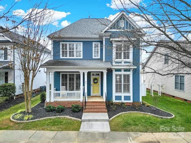 view of front of house with a shingled roof and a front lawn