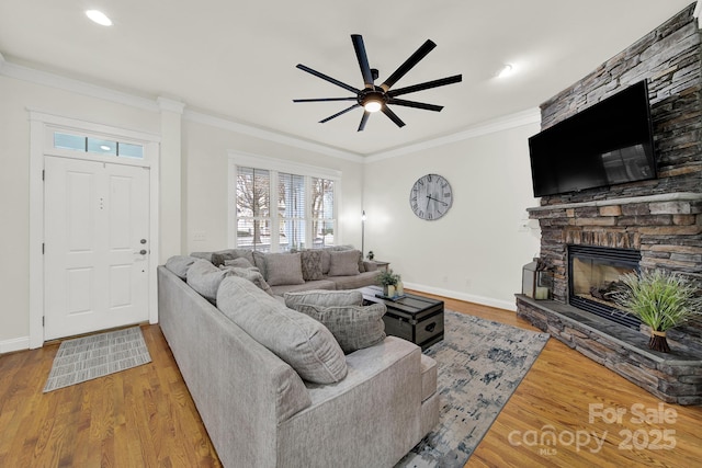 living room with a fireplace, baseboards, wood finished floors, and crown molding