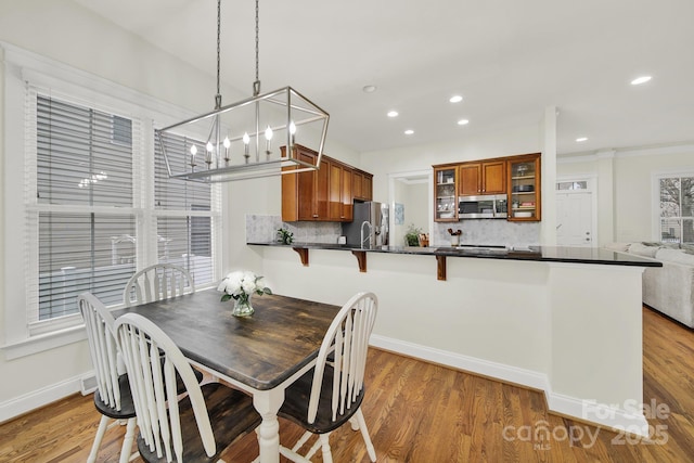 dining space with baseboards, wood finished floors, and recessed lighting