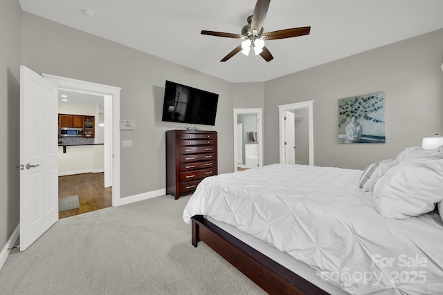 bedroom with ensuite bath, baseboards, a ceiling fan, and light colored carpet