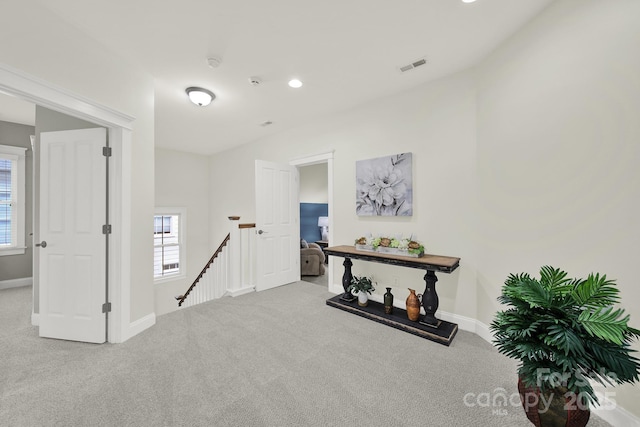 interior space with baseboards, visible vents, an upstairs landing, and carpet floors