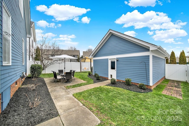 back of house featuring a gate, a fenced backyard, a yard, and a patio