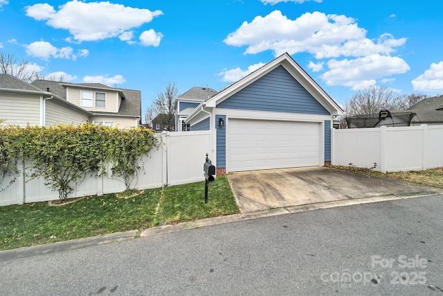 garage featuring fence and concrete driveway