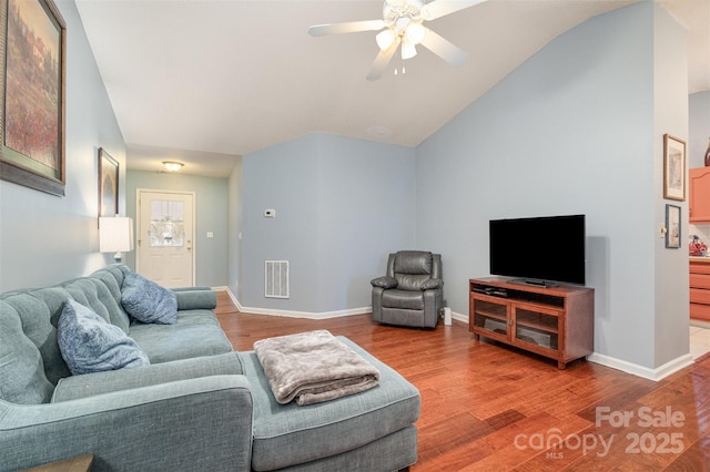 living area featuring lofted ceiling, wood finished floors, visible vents, and baseboards